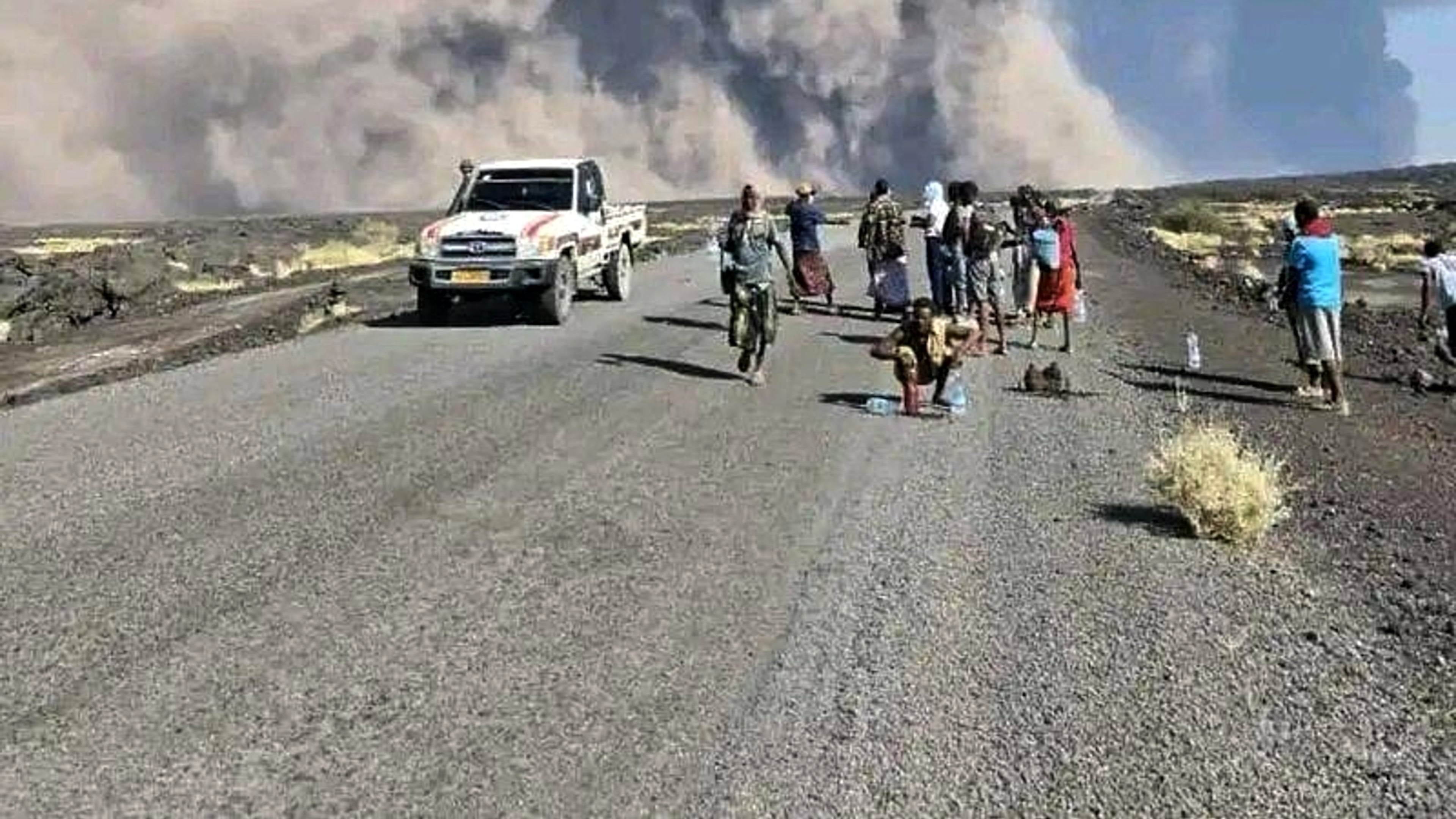 In this photo released by the Afar Government Communication Bureau, people watch ash billow from the first time eruption of the Hayli Gubbi Volcano in Ethiopia's Afar region Sunday, Nov. 23, 2025. (Afar Government Communication Bureau via AP)