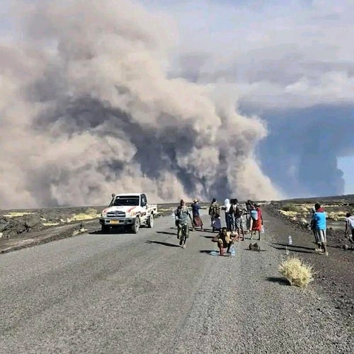In this photo released by the Afar Government Communication Bureau, people watch ash billow from the first time eruption of the Hayli Gubbi Volcano in Ethiopia's Afar region Sunday, Nov. 23, 2025. (Afar Government Communication Bureau via AP)
