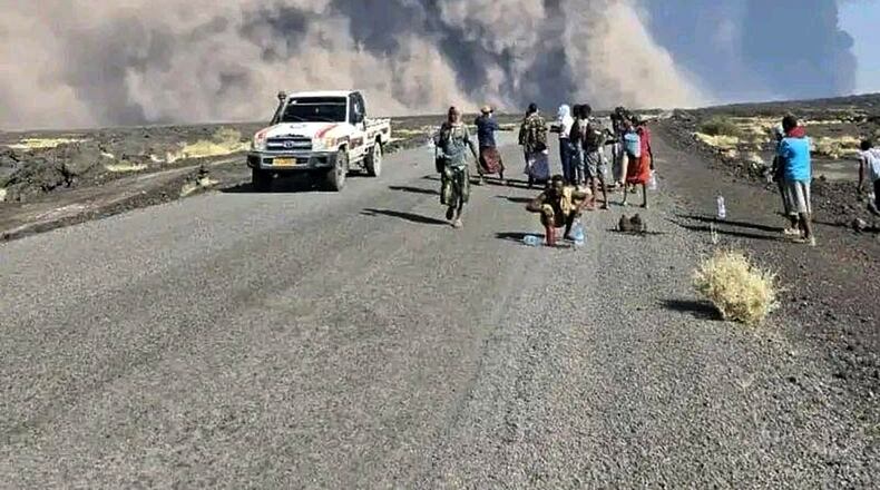 In this photo released by the Afar Government Communication Bureau, people watch ash billow from the first time eruption of the Hayli Gubbi Volcano in Ethiopia's Afar region Sunday, Nov. 23, 2025. (Afar Government Communication Bureau via AP)