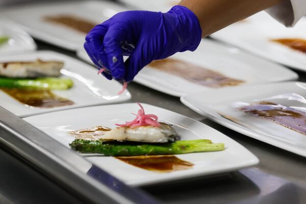 A student adds red onion as garnish to a plated dish. (Abbey Cutrer/AJC)