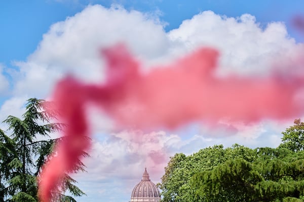 Pink smoke rises in front of St. Peter's Dome during a protest by the Women's Ordination Conference, calling for full equality for women in the Catholic Church on the first day of the conclave to elect the 267th pope, in Rome, Wednesday, May 7, 2025. (AP Photo/Bernat Armangue)