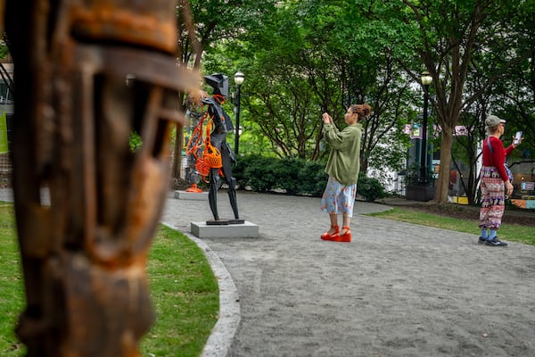 Visitors admire the sculptures of Olu Amoda, an Alpharetta-based Nigerian artist who is currently featured in Woodruff Park as part of the Art in the Park series. (Jeffrey Moustache/AJC)