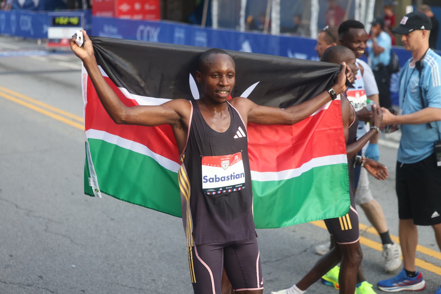Sebastian Sawe celebrates win at the finish of the 55th running of the Atlanta Journal-Constitution Peachtree Road Race in Atlanta on Thursday, July 4, 2024.   (Jason Getz / AJC)