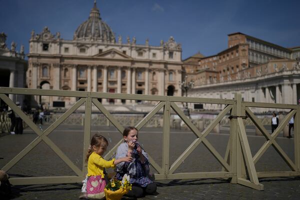 Margaret, left, and Sara from Slovakia sit at St. Peter's Square in front of St. Peter's Basilica where the body of Pope Francis will lie in state for three days, Wednesday, April 23, 2025. (AP Photo/Markus Schreiber)