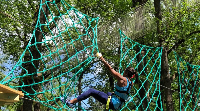 Participant tests her strength and fear of heights on this vertical cargo net.