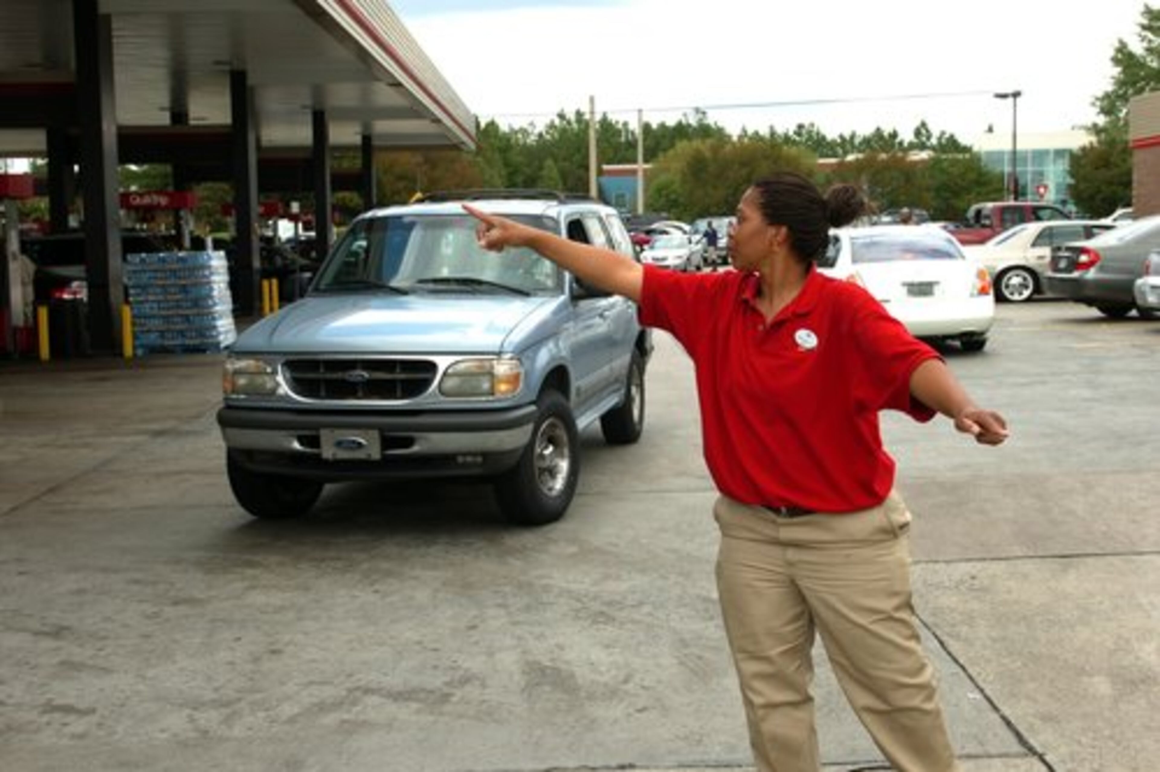 QuikTrip employee Tenisha Johnson directs drivers as she tries to find an open pump as traffic backs up on Panoia Road in south DeKalb County.
