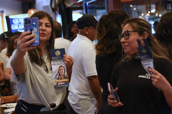 Attendees pose for photos holding a campaign pamphlet of Rep. Mikie Sherrill, D-N.J., during a "Get Out the Vote" rally, Saturday, June 7, 2025, in Elizabeth, N.J. (AP Photo/Heather Khalifa)
