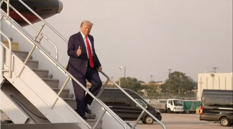 Former president Donald Trump gives a thumbs-up while exiting his plane at Hartsfield-Jackson International Airport.