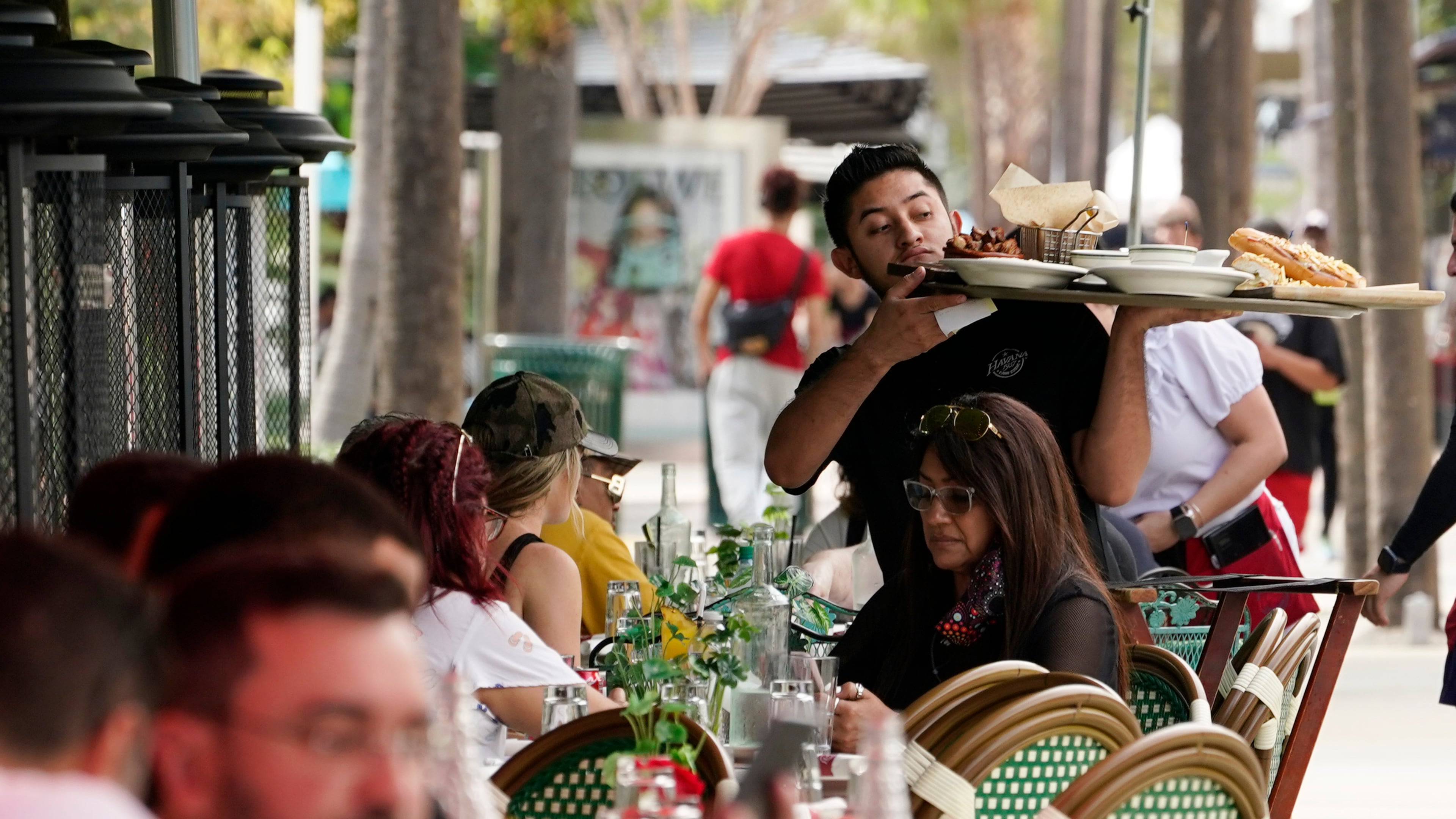 FILE - A waiter delivers food to patrons at a restaurant, Jan. 21, 2022, in Miami Beach, Fla. (AP Photo/Marta Lavandier, File)