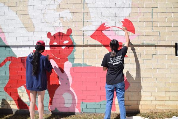 North Gwinnet High School students Ellina Jung, left, and Kayla Eyles paint a portion of the mural on April 15. (Courtesy of Curt Yeomans)