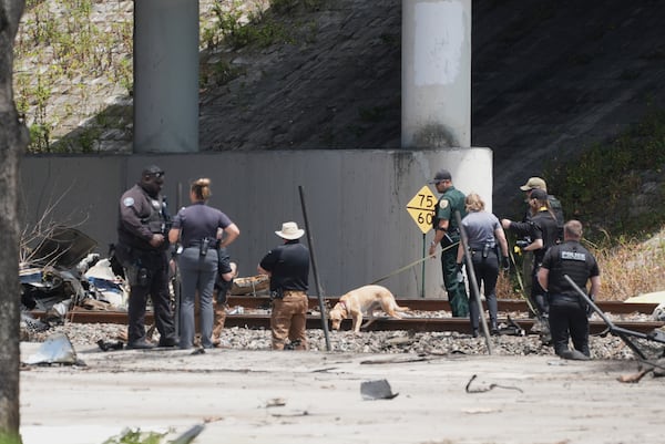 Emergency personnel respond to the area where a small plane crashed on the railroad tracks beneath the overpass near Interstate 95 in Boca Raton, Fla., on Friday, April 11, 2025. (AP Photo/Marta Lavandier)