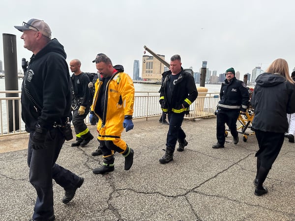 First responders walk along Pier 40, Thursday, April 10, 2025, in New York, across from where a helicopter went down in the Hudson River in Jersey City, N.J. (AP Photo/Jennifer Peltz)