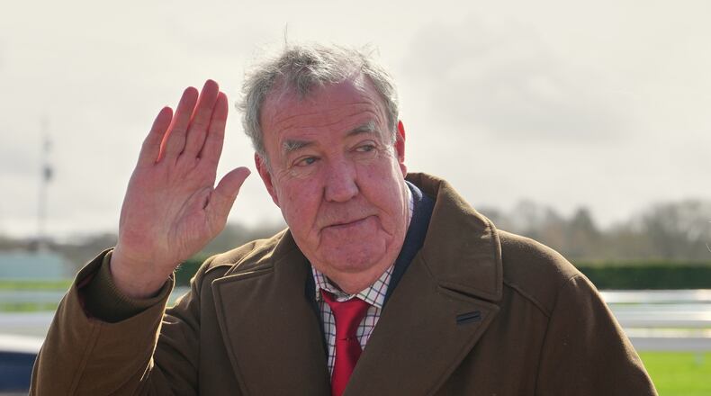 FILE - TV presenter Jeremy Clarkson waves to the media as he arrives on day four of the 2026 Cheltenham Festival in Cheltenham, England, on March 13, 2026. (AP Photo/Dave Shopland, File)