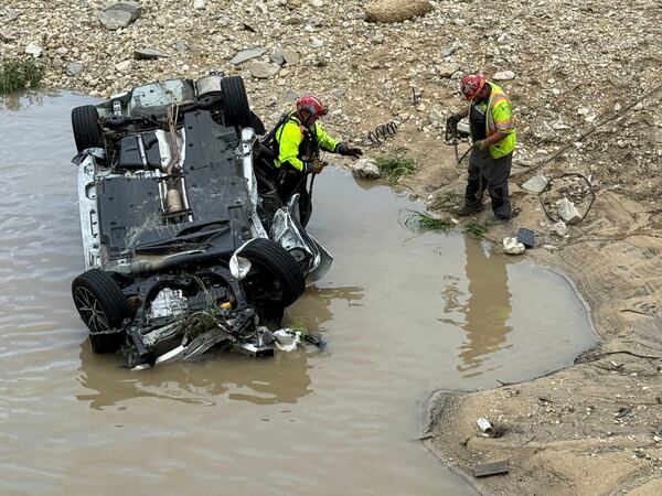 A crew works near a vehicle that was swept away in floodwaters in San Antonio, Texas, on Thursday, June 12, 2025. (AP Photo/Lekan Oyekanmi)