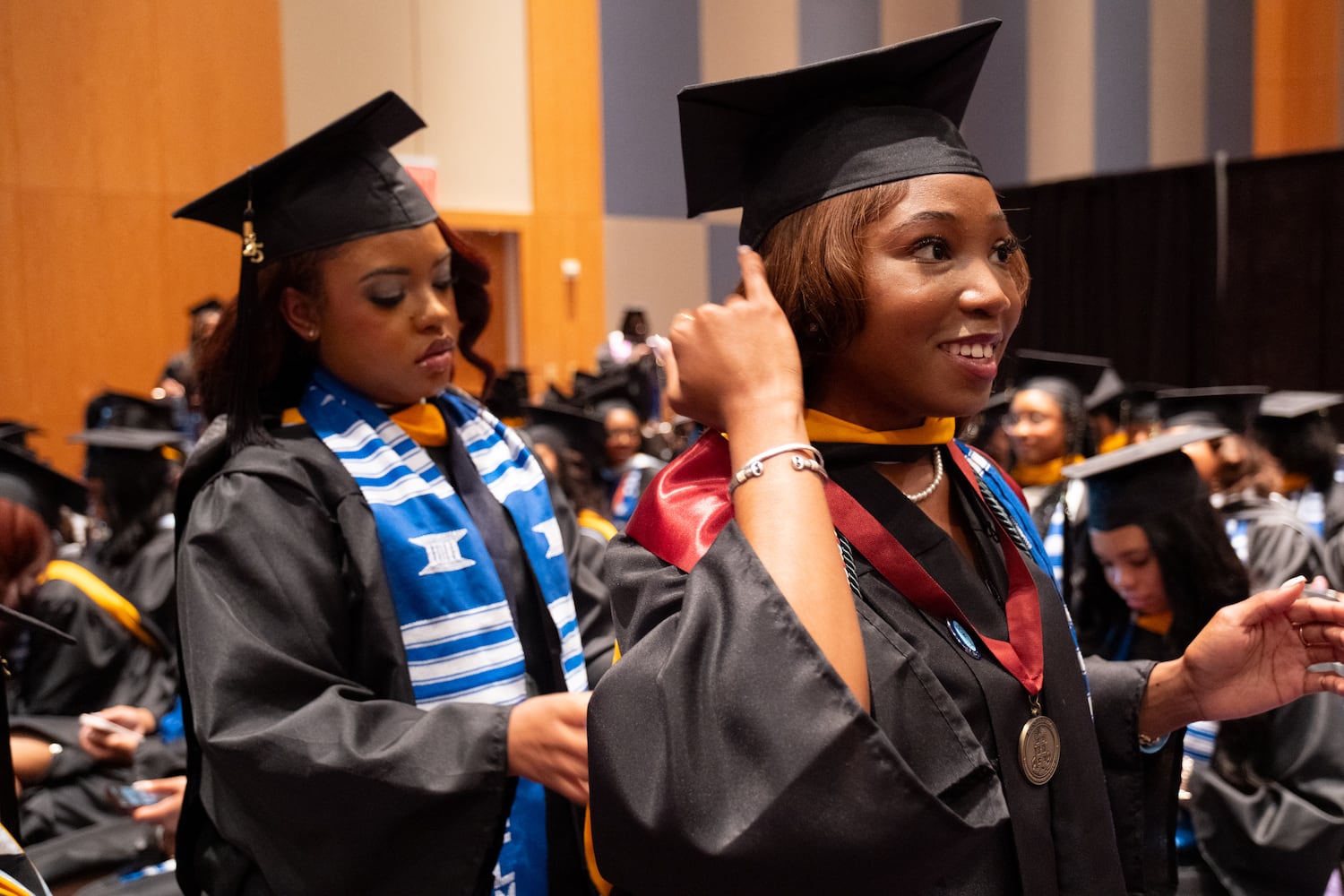 Jamecia Phillips, left, helps arrange Zahrria Thomas’ gown and sashes before the start of the Spelman College graduation ceremony at the Georgia International Convention Center in College Park on Sunday, May 18, 2025.   Ben Gray for the Atlanta Journal-Constitution