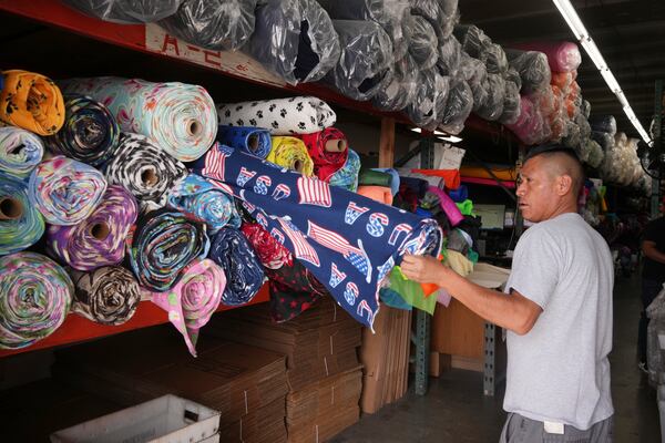 A worker displays textiles in the fashion district Thursday, April 3, 2025, in Los Angeles. (AP Photo/Damian Dovarganes)