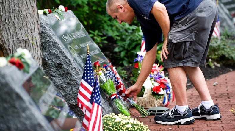 Chris Petraglia of Middletown puts flowers at the memorial stone of Louis J. Minervino while visiting the Middletown World Trade Center Memorial Gardens on the 10th anniversary of the 9/11 terror attacks, Sunday Sept. 11, 2011 in Middletown, NJ. (AP Photo/Joe Epstein)