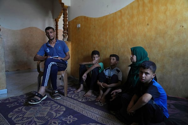 Hatem Al-Nouri, the father of two children who were killed, and one injured, in an Israeli strike while waiting to receive nutritional supplements at a medical clinic, sits with his family during an interview at his home in Deir al-Balah, Gaza Strip, Friday, July 11, 2025. (AP Photo/Abdel Kareem Hana)