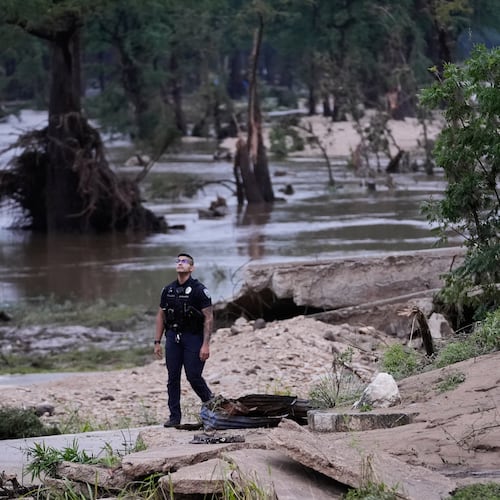 A police officer walks along the Guadalupe River after a series of storms on Friday, July 17, 2026, in Kerrville, Texas. (AP Photo/Gerald Herbert)