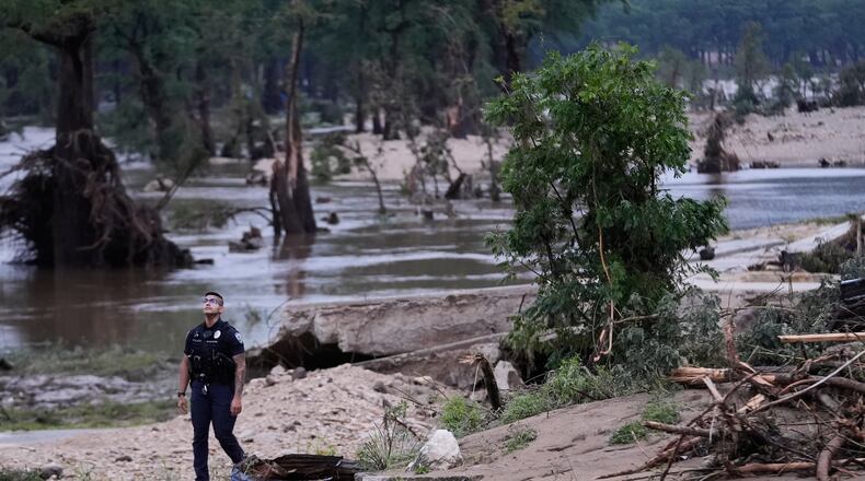 A police officer walks along the Guadalupe River after a series of storms on Friday, July 17, 2026, in Kerrville, Texas. (AP Photo/Gerald Herbert)