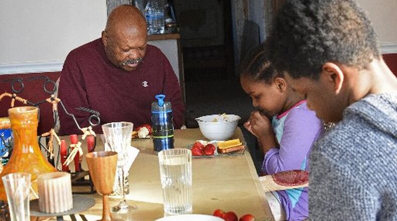 Eugene Vickerson and his grandchildren Jakari and Amore, shown in a 2016 file photo, pray together before eating breakfast. Georgia has increased its efforts to place children with grandparents or other relatives. HYOSUB SHIN / HSHIN@AJC.COM