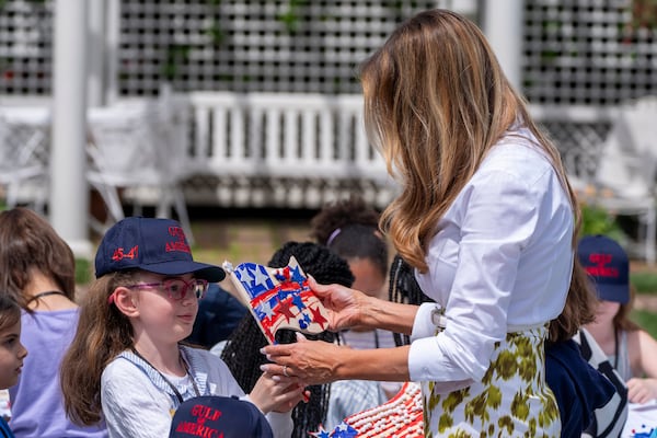 First lady Melania Trump looks at a decorated flag as she participates in flag decorating during a Take Our Child to Work Day event in the Jacqueline Kennedy Garden at the White House, Tuesday, May 20, 2025, in Washington. (AP Photo/Alex Brandon)