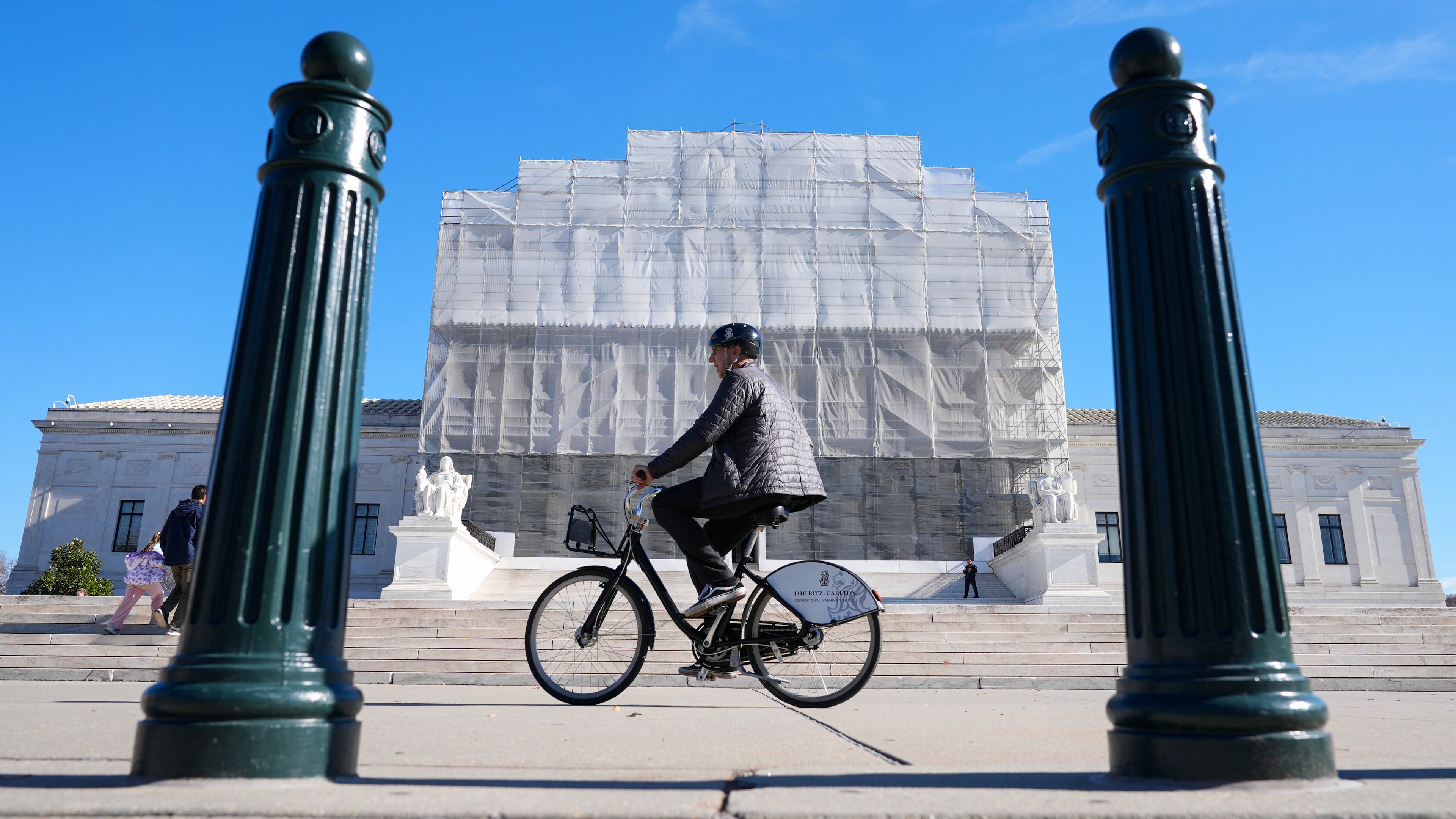 As a person on a bicycle rides past, construction on the front of the U.S. Supreme Court continues Monday, Nov. 24, 2025, in Washington. (AP Photo/Mariam Zuhaib)