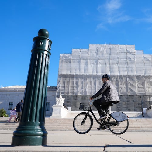 As a person on a bicycle rides past, construction on the front of the U.S. Supreme Court continues Monday, Nov. 24, 2025, in Washington. (AP Photo/Mariam Zuhaib)