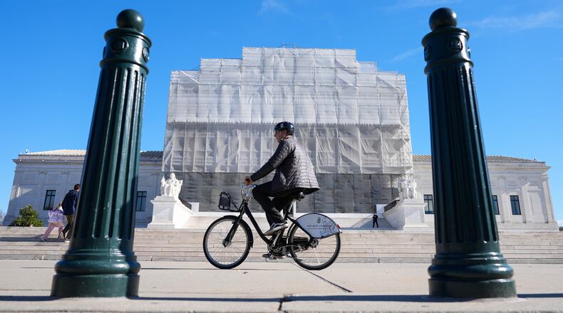 As a person on a bicycle rides past, construction on the front of the U.S. Supreme Court continues Monday, Nov. 24, 2025, in Washington. (AP Photo/Mariam Zuhaib)
