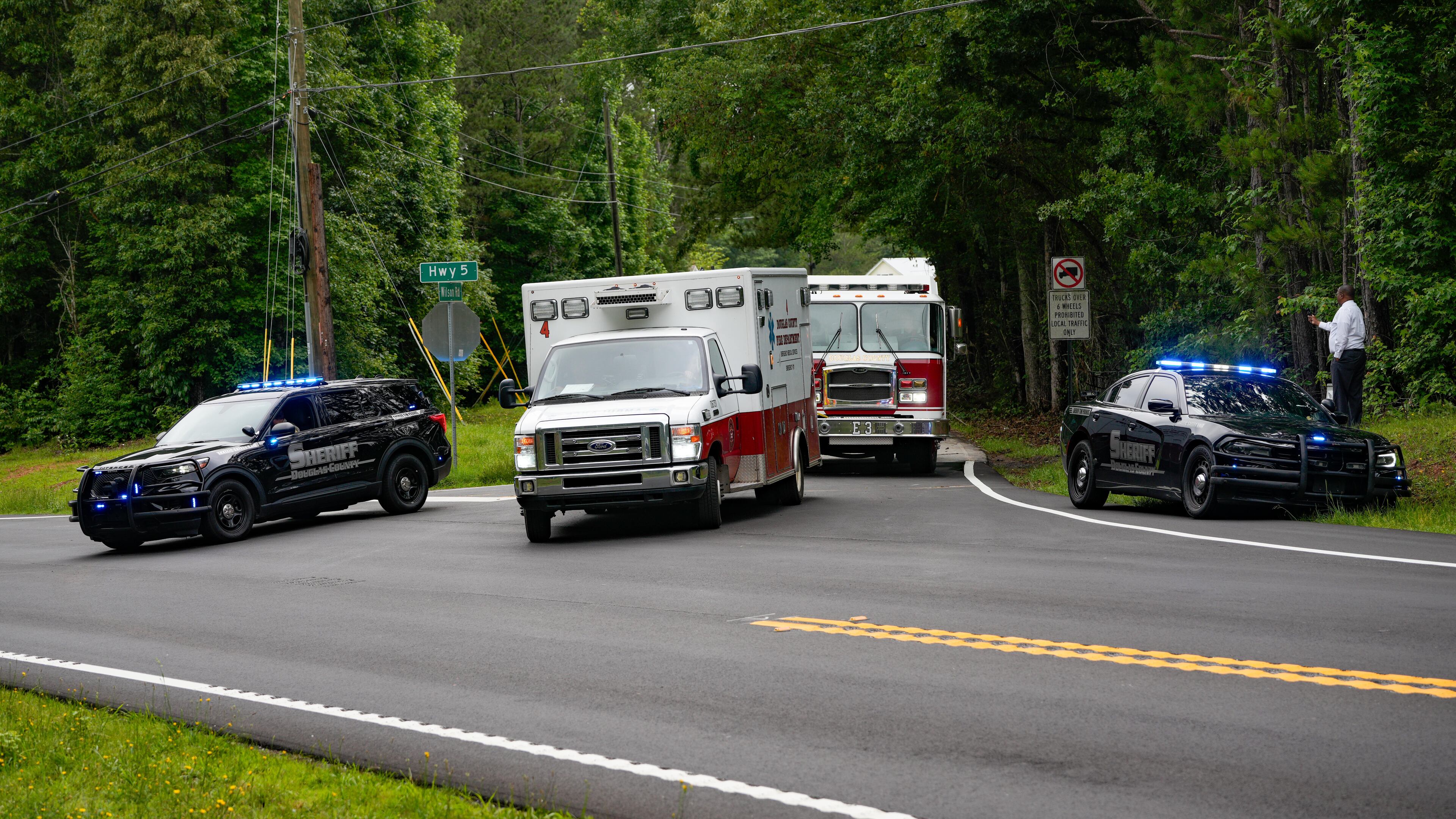 Law enforcement vehicles block Wilson Road in Douglas County after a big rig overturned. The truck was carrying hazardous materials, and officials asked nearby residents to evacuate Friday. (Ben Hendren for The AJC)