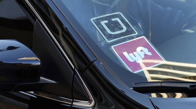 A ride-share car displays Lyft and Uber stickers on its front windshield in downtown Los Angeles. A North Georgia Republican has introduced legislation that would allow Lyft and Uber drivers to keep firearms in their cars. (AP Photo/Richard Vogel, File)