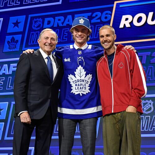 Gavin McKenna, center, stands with NHL Commissioner Gary Bettman, left, and singer Justin Bieber, right, after being drafted by the Toronto Maple Leafs during the NHL hockey draft Friday, June 26, 2026, in Buffalo, N.Y. (AP Photo/Adrian Kraus)