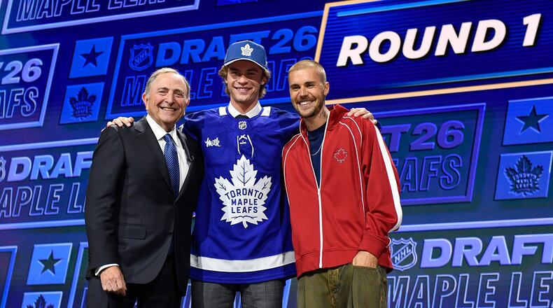 Gavin McKenna, center, stands with NHL Commissioner Gary Bettman, left, and singer Justin Bieber, right, after being drafted by the Toronto Maple Leafs during the NHL hockey draft Friday, June 26, 2026, in Buffalo, N.Y. (AP Photo/Adrian Kraus)
