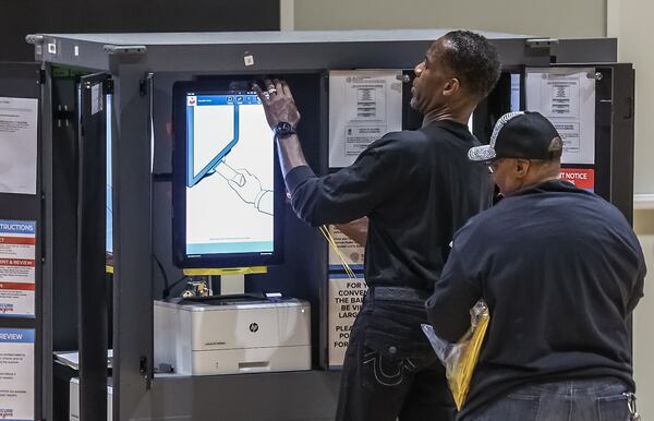Poll workers Lon Perdue (left) and Ruth Hardy prepare voting machines at the Harp Student Center on Tuesday, Nov. 5, 2024, in Buckhead. Conservative activists began pushing to scrap Georgia’s touchscreen voting system in the aftermath of Donald Trump’s narrow 2020 loss. (John Spink/AJC 2024)
