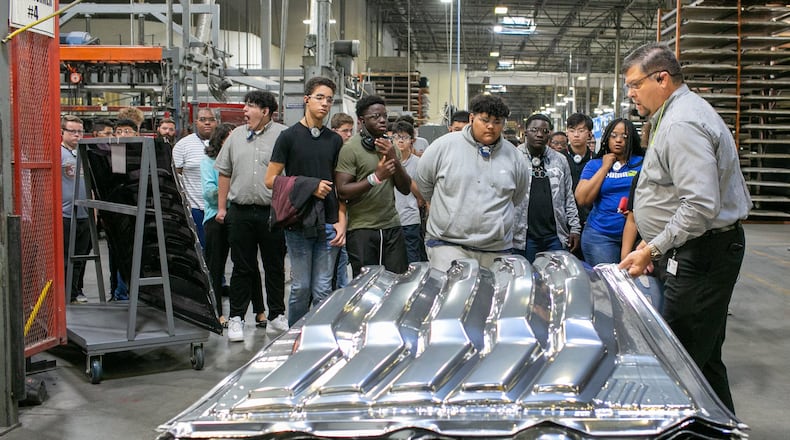 Vice President of Operations Chris Fann (right) shows a product to high school students at Lund International in Lawrenceville on Thursday, Oct. 3, 2019.