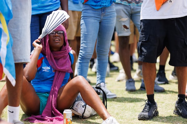 A Congo fan tries to shielf herself from the sun with a paper fan while at the FIFA Fan Fest in Centennial Park on July 1, 2026. (Estela Muñoz/AJC)