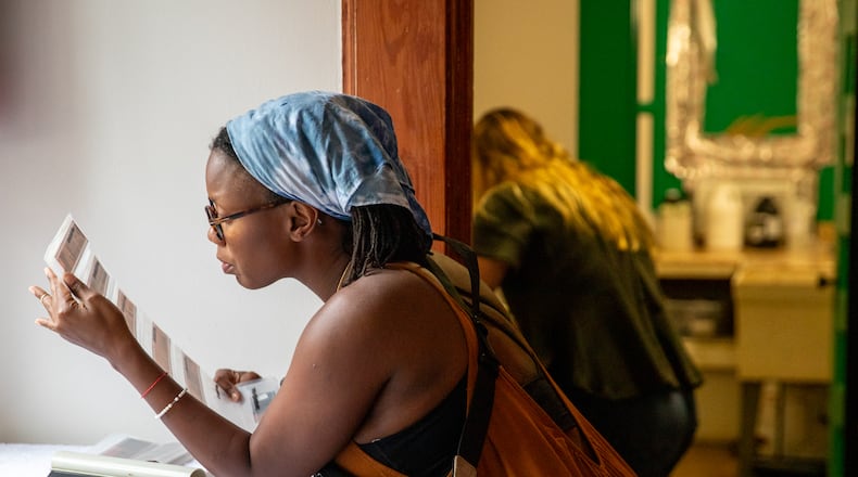 Lauren Jones, of Buckhead, looks over negatives her Grandfather took during a film photography darkroom class at Callanwolde Fine Arts Center on Thursday, June 29, 2023. Jones later printed the negatives in the darkroom. (Jenni Girtman for The Atlanta Journal-Constitution)