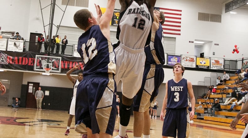 Alpharetta player Devontae Cacok (12), center, goes in for a lay-up while covered up by West Forsyth player John Conway (12) and another player on Friday, Feb. 7, 2014, in Alpharetta, Ga. BRANDEN CAMP/SPECIAL