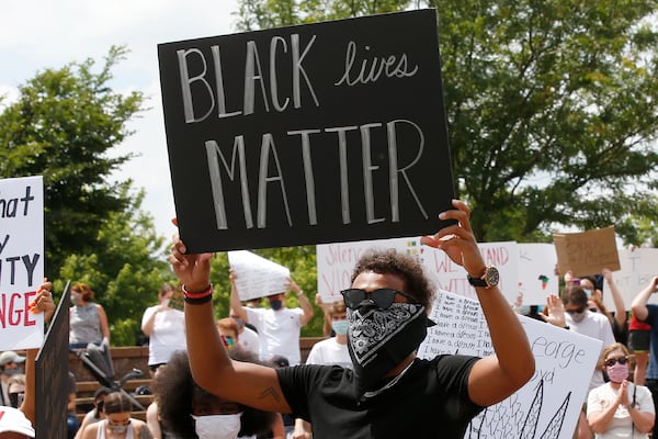 FILE - In this June 1, 2020, file photo, Atlanta Hawks guard Trae Young holds a "Black Lives Matter" sign during a peaceful rally in his hometown of Norman, Okla., calling attention to the killing of George Floyd. While NBA players are using the season restart to demand change; coaches in the league are not making them walk down that path alone. (AP Photo/Sue Ogrocki, File)
