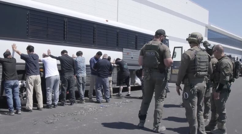 FILE - This image from video provided by U.S. Immigration and Customs Enforcement via DVIDS shows manufacturing plant employees waiting to have their legs shackled at the Hyundai Motor Group's electric vehicle plant, Sept. 4, 2025, in Ellabell, Ga. (Corey Bullard/U.S. Immigration and Customs Enforcement via AP, File)