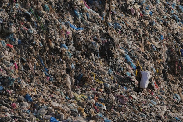 A Palestinian child search through a landfill for firewood, plastic, and canned goods in Al-Zawaideh, Gaza Strip, on Tuesday, June 24, 2025. (AP Photo/Abdel Kareem Hana)