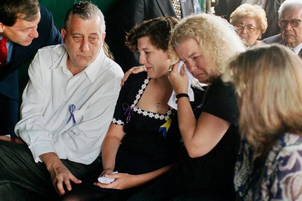 FILE - Aren Almon, center, whose daughter Baylee became a national symbol in an iconic photo of a firefighter holding her lifeless body following the bombing of the federal building in Oklahoma City, is comforted by her father Tommy Almon and mother Debbie Almon, during a funeral service for Baylee at Arlington Memorial Park Cemetery in Oklahoma City, April 24, 1995. (AP Photo/Pat Sullivan, File)