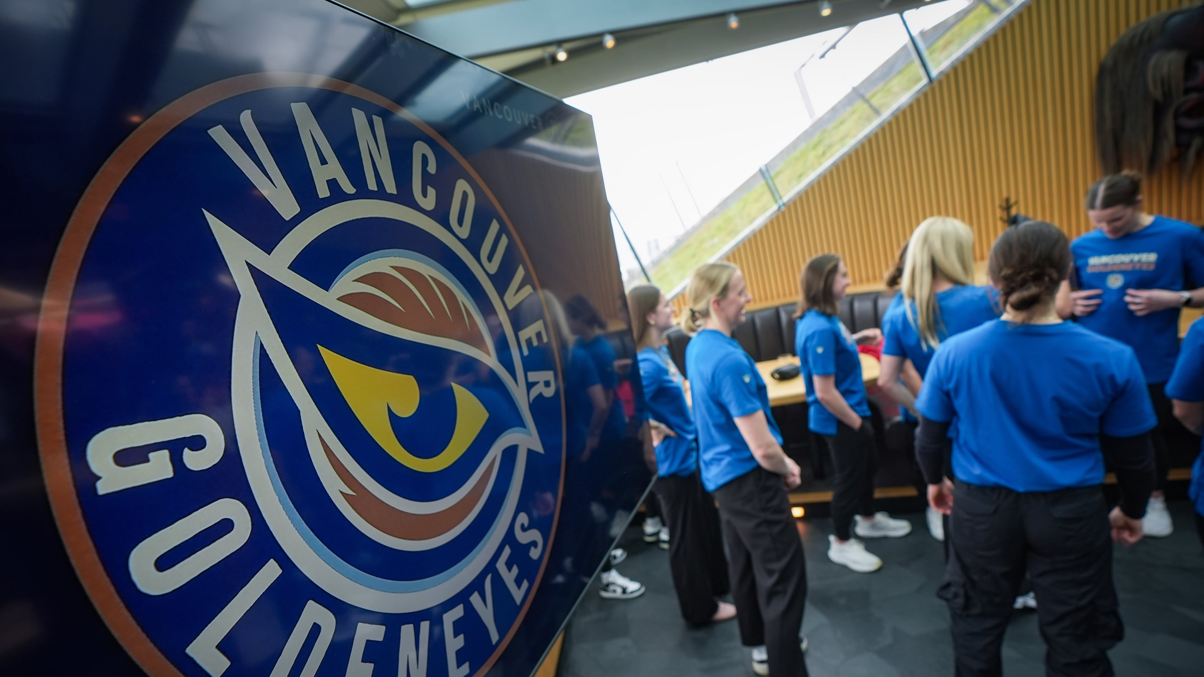 Vancouver Goldeneyes players stand near a display showing their new logo and team name following an unveiling at a PWHL hockey news conference, Thursday, Nov. 6, 2025, in Vancouver, British Columbia. (Darryl Dyck/The Canadian Press via AP)