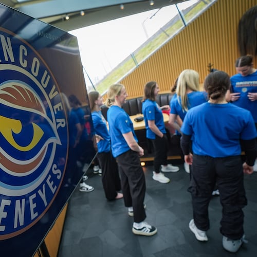 Vancouver Goldeneyes players stand near a display showing their new logo and team name following an unveiling at a PWHL hockey news conference, Thursday, Nov. 6, 2025, in Vancouver, British Columbia. (Darryl Dyck/The Canadian Press via AP)