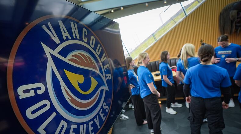 Vancouver Goldeneyes players stand near a display showing their new logo and team name following an unveiling at a PWHL hockey news conference, Thursday, Nov. 6, 2025, in Vancouver, British Columbia. (Darryl Dyck/The Canadian Press via AP)