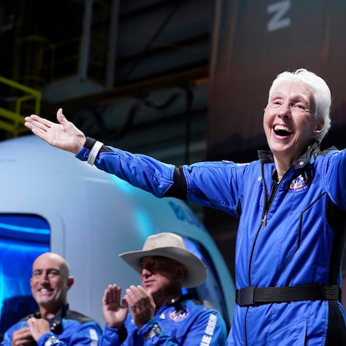 FILE - Wally Funk, right, describes her flight experience as Mark Bezos, left, and Jeff Bezos, left, center, applaud in the spaceport near Van Horn, Texas, July 20, 2021. (AP Photo/Tony Gutierrez, File)