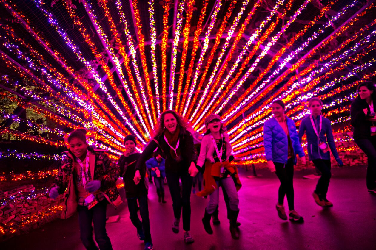 Aiden Harte (left), his mother Lisa and Eliza Peterson hold hands as they run underneath holiday lights inside Six Flags Over Georgia in Austell on Friday, November 21, 2014. The park was decorated in 10 sections of holiday lights for the first time since 1990. (Jonathan Phillips/Special)