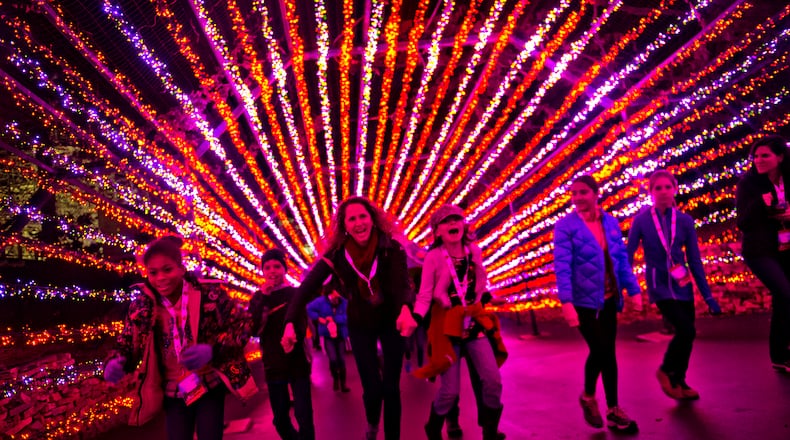Aiden Harte (left), his mother Lisa and Eliza Peterson hold hands as they run underneath holiday lights inside Six Flags Over Georgia in Austell on Friday, November 21, 2014. The park was decorated in 10 sections of holiday lights for the first time since 1990. (Jonathan Phillips/Special)