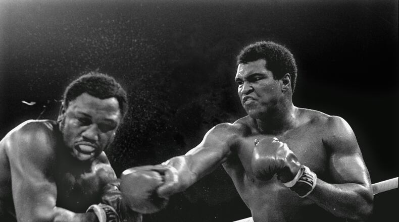 In this Oct. 1, 1975 file photo, spray flies from the head of challenger Joe Frazier, left, as heavyweight champion Muhammad Ali connects with a right in the ninth round of their title fight in Manila, Philippines. (AP Photo/Mitsunori Chigita, File)