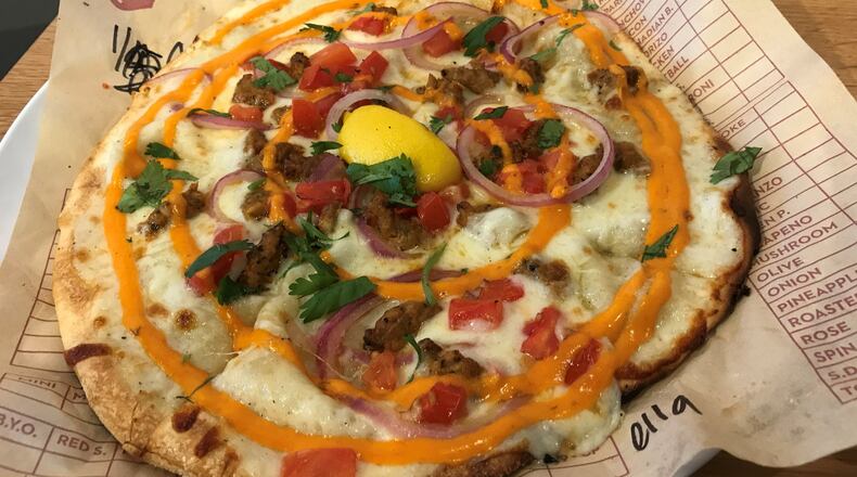 At MOD Pizza, you can build your own or try one of the restaurant’s creations, including a seasonal pie such as Ella (pictured) that holds white sauce, mozzarella, spicy chicken sausage, diced tomatoes, red onion, cilantro, a lemon wedge and Sriracha. LIGAYA FIGUERAS / LFIGUERAS@AJC.COM